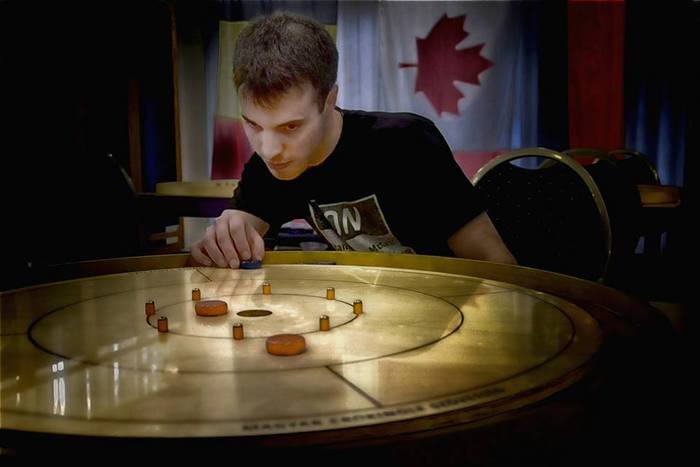 Nathan Walsh poses for an artistic shot on the official Hungarian Crokinole Federation board